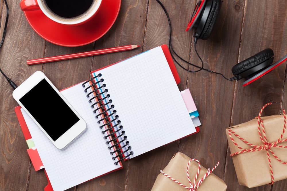 Office wooden desk with notepad, smartphone and gift boxes. Top view with copy space