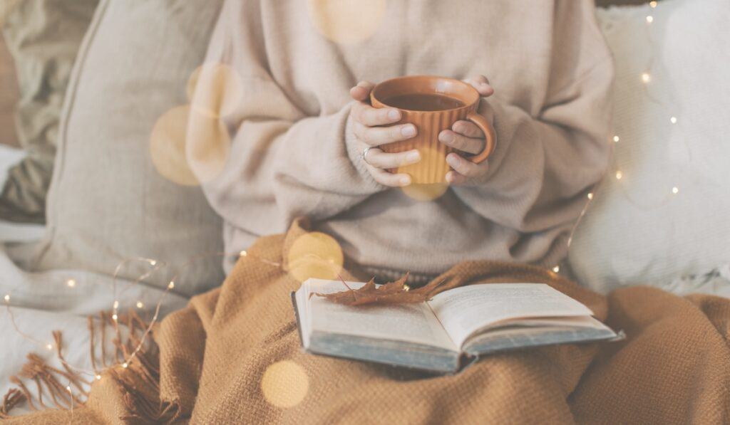 woman in sweater holding mug of tea.