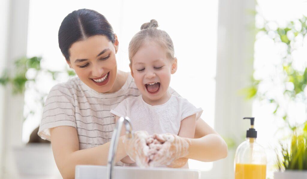 mom helping daughter wash her hands